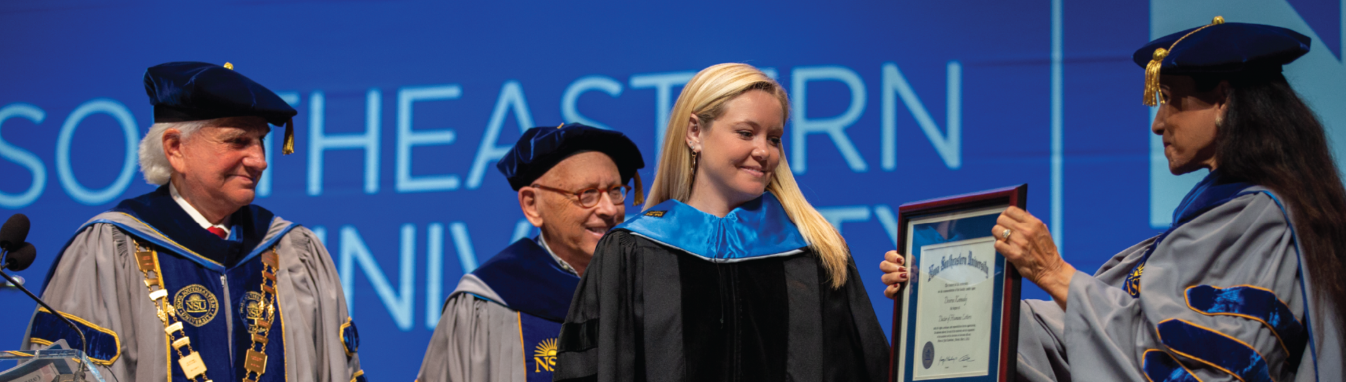 Board at graduation presenting placard to students