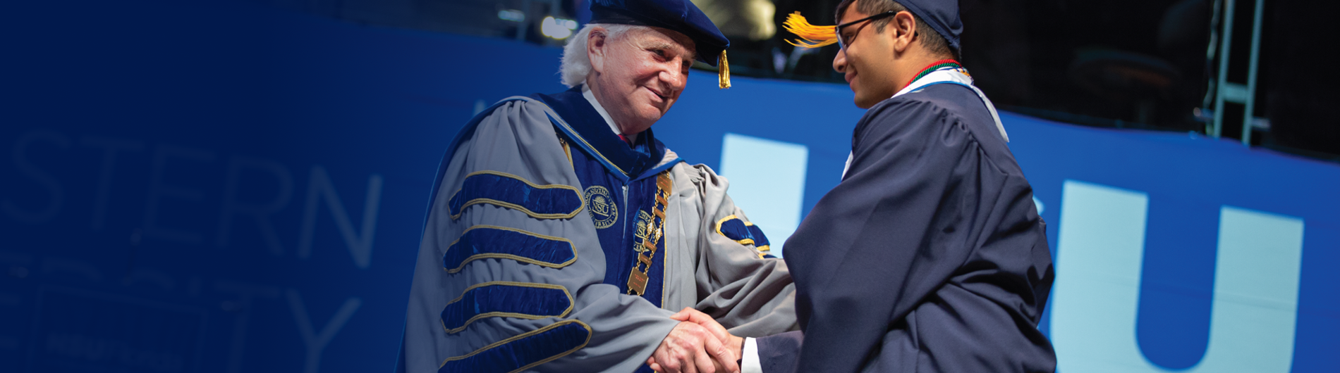 President Hanbury shaking a graduate's hand on stage.