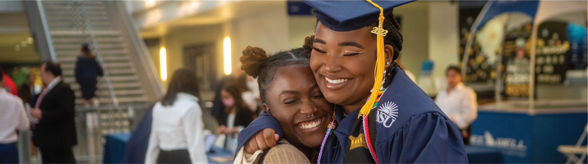 An NSU graduate celebrating and hugging with her little sister