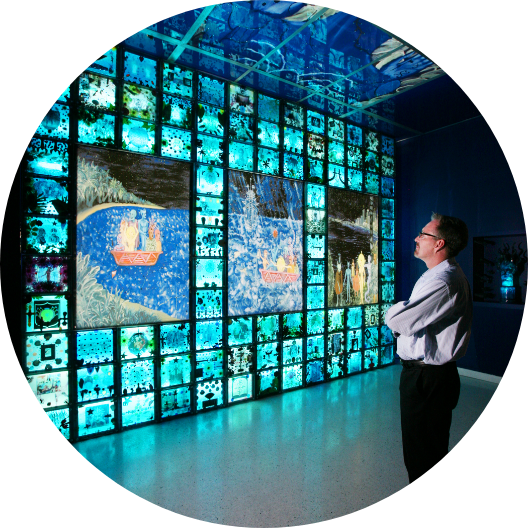 man looking at a wall of photographs in an art museum