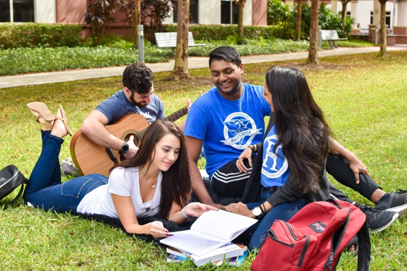 a group of diverse students studying and playing music in the courtyard