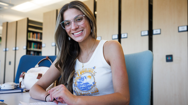 NSU student smiling sitting on desk