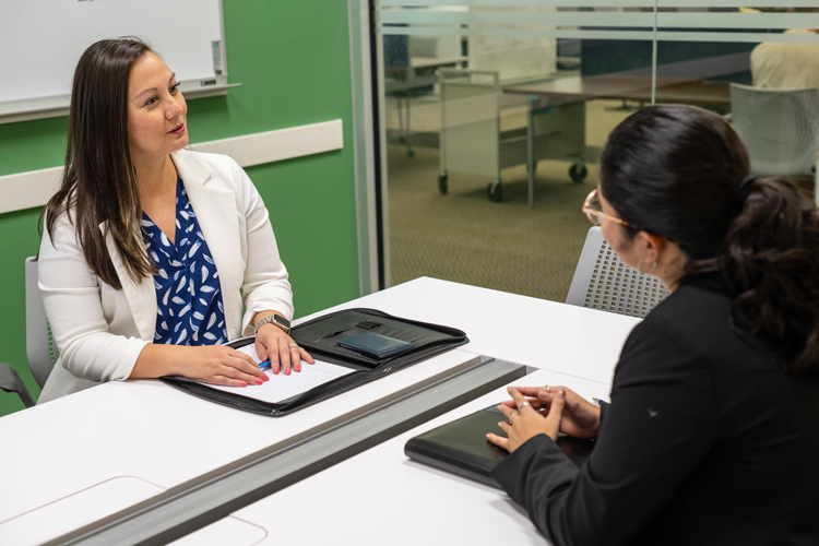Advisor speaking with student at table