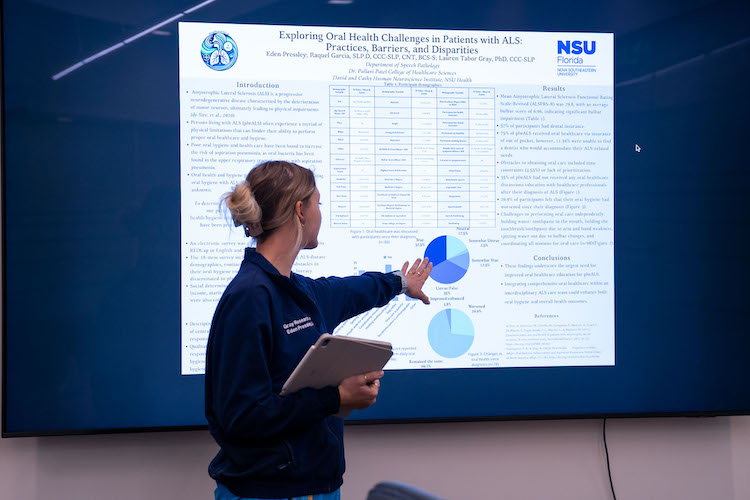 Student presenting research on large monitor.