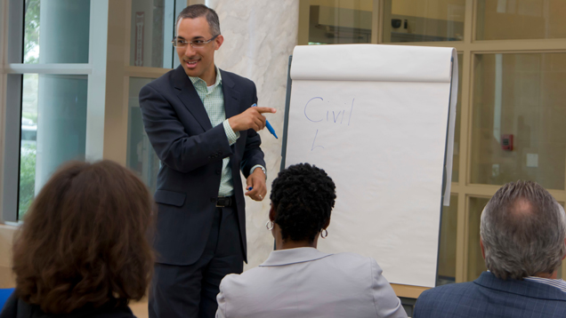 Faculty pointing to notepad board and speaking
