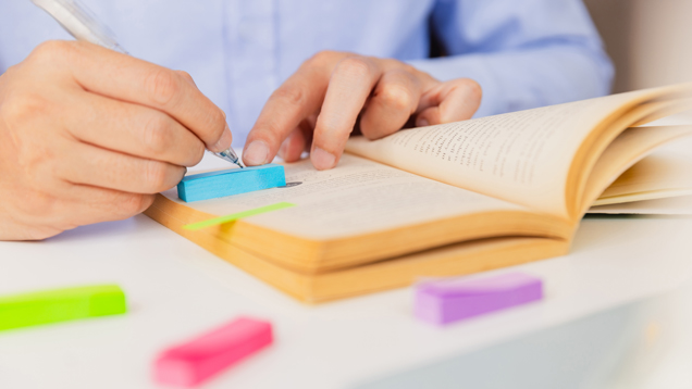 Faculty working using sticky note to bookmark closeup