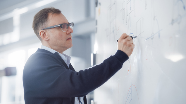 Mathematical professor writing graphs on board