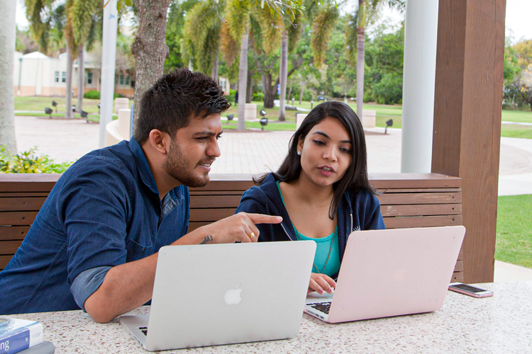 NSU members looking at computer screen in campus outdoors