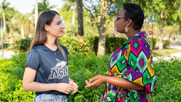 Student and professor talking outdoors on campus