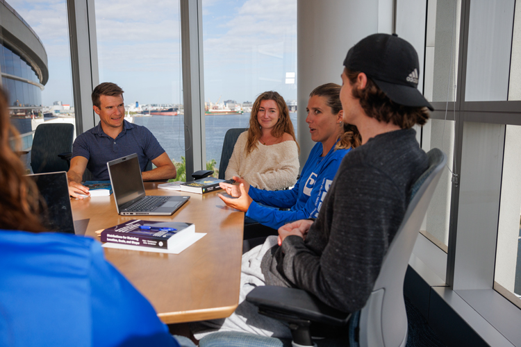 Students speaking in desk classroom with window city view