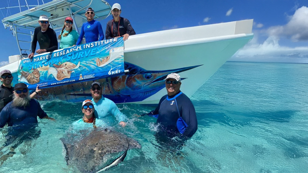 People and stingrey next to harvey research boat