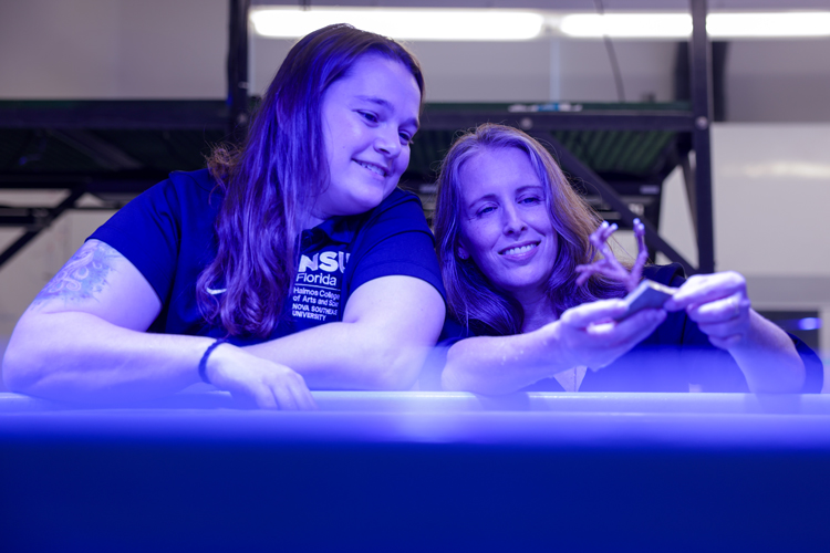 Two people at NSU biology coral lab with blue lighting