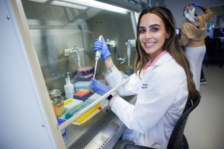 White lab coat person at ocean lab using pipette