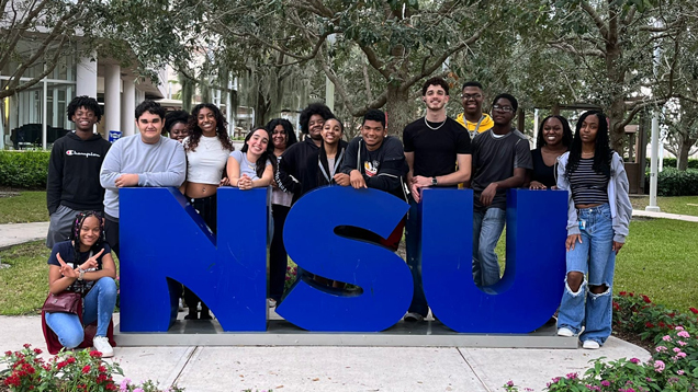 Students in the 2023 NSU Knowledge for Freedom program standing behind large NSU letters