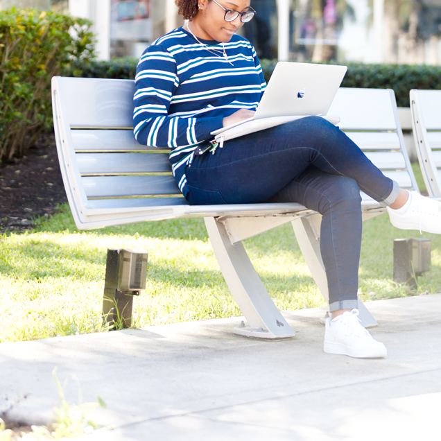 Student sitting on bench with laptop
