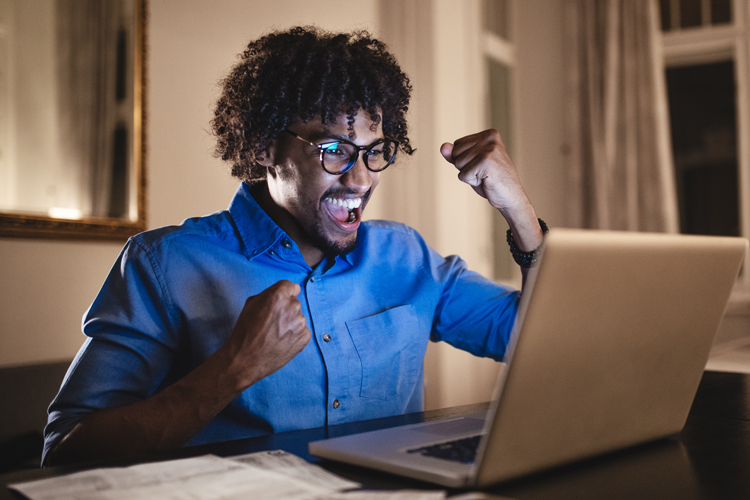 Employee cheering about discount program in front of computer