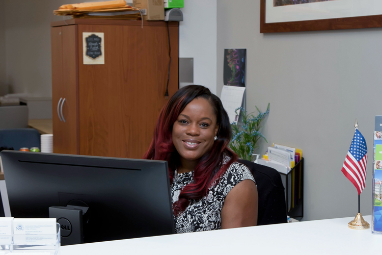 NSU employee sitting at desk smiling