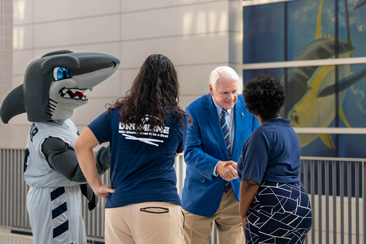 NSU president with shark mascot welcoming new university members