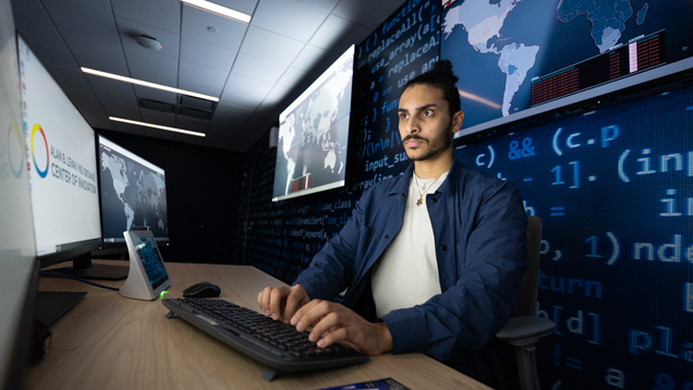 Student typing in computer at Levan Centerr Cybersecurity room