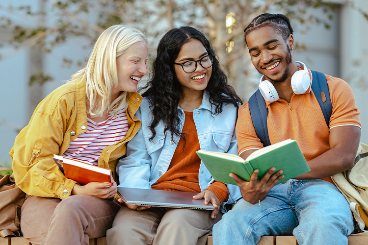 Group of students sitting on a bench and reading a book