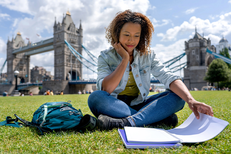 Student studying abroad in London sitting in front of Tower Bridge
