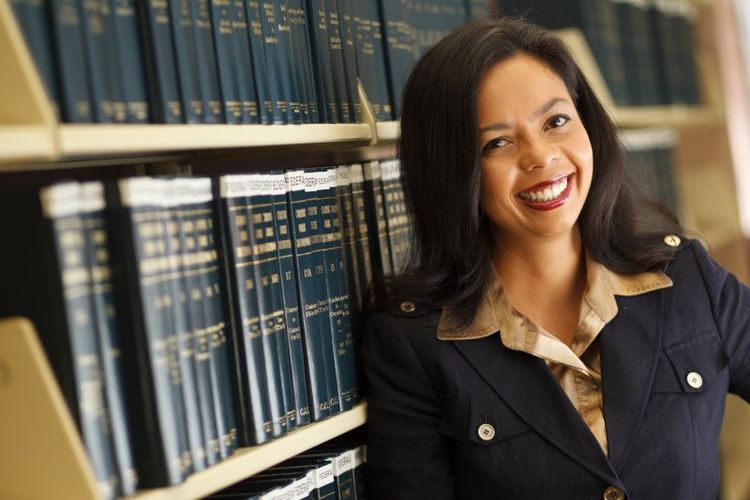 NSU law student leaning on library shelves
