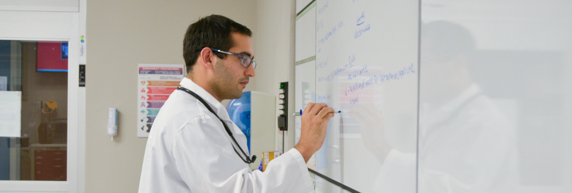 NSU MD male student writing on classroom board