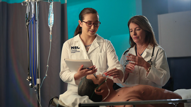 Student putting oxigen mask on medical dummy