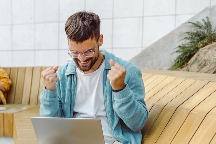 Excited male student looking at laptop screen receiving university admission good news 