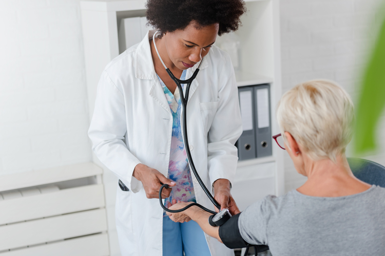 Medical lady checking blood pressure to elderly patient