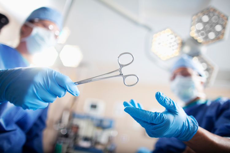 Physician assistant on surgery passing tools to surgeon