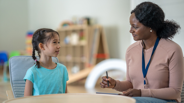 Caring psychologist listening to child on therapy day