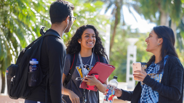 Three students smiling and speaking