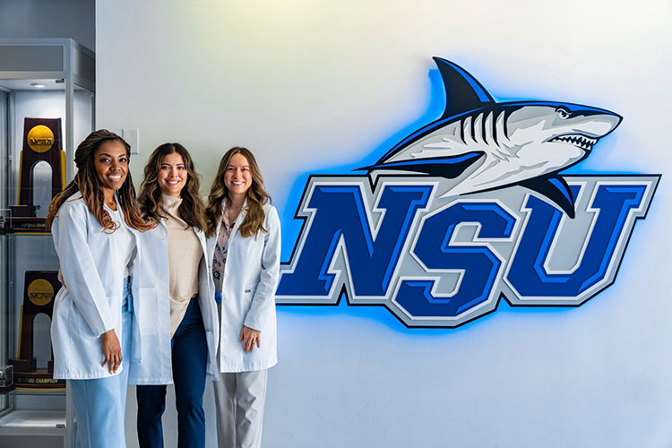 Students posing next to NSU Athletics logo