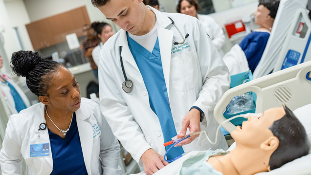 Student nursing learning in simulation lab with professor guiding