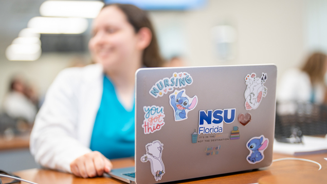 Nursing student in class with nsu nursing theme stickers laptop