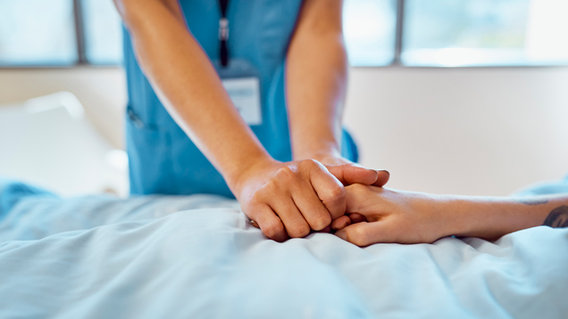 Passionate nurse professional holding patient's hand in comfort on bed