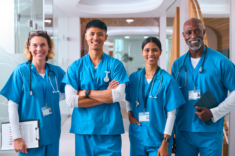 Smiling multi cultural nurses team wearing scrubs in hospital