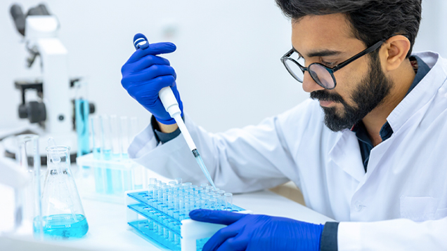 Scientist dripping liquid into test tubes