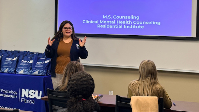 Graduate student standing at front of room presenting at Residential Institute.