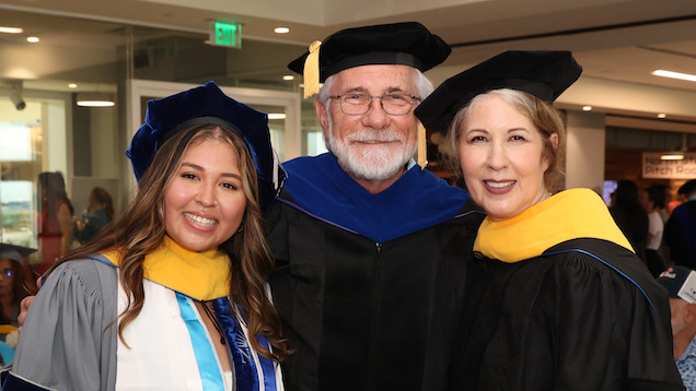 Student and two faculty in commencement regalia
