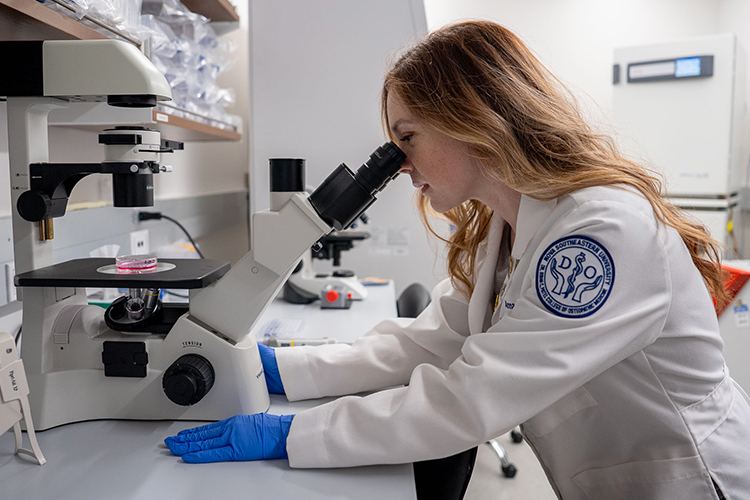 NSU researcher using a microscope in a lab