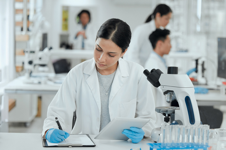 Scientist taking notes while her team works in the lab