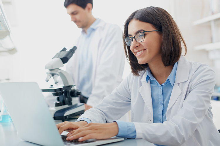 Scientist typing on her laptop in a lab