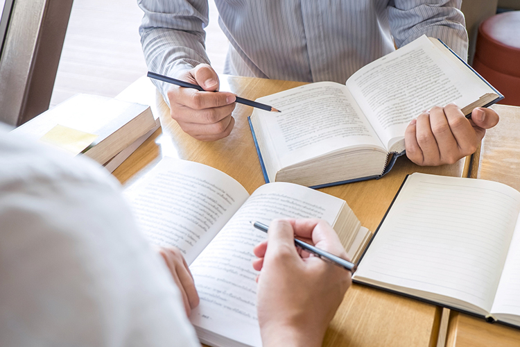 Two men sitting at a table reading books close up