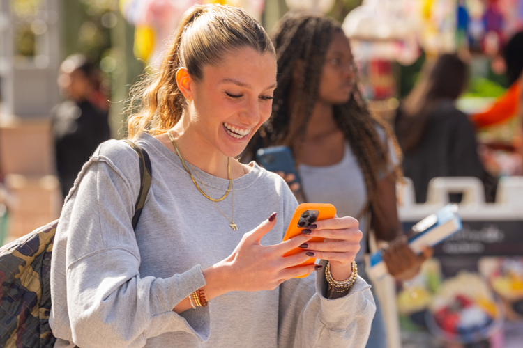 NSU student using phone looking at marketing