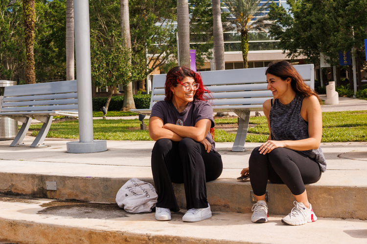 Two students speaking on campus outdoors
