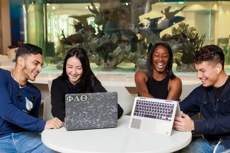 Happy group of students using laptops