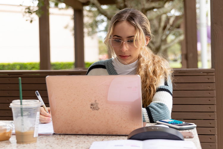 NSU student using a laptop outdoors.