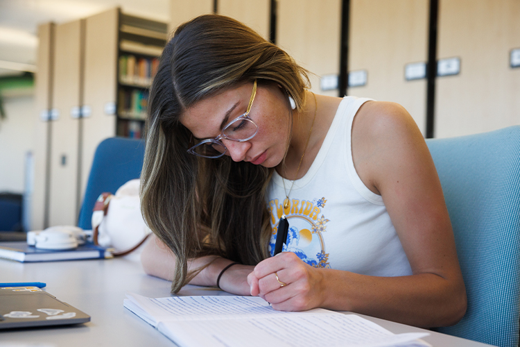 NSU student writing in a notebook